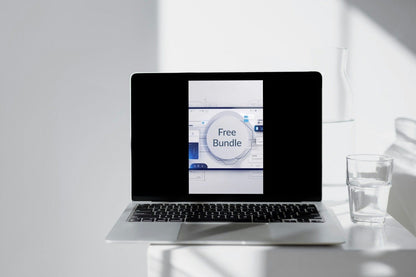 Laptop on a white surface with a glass of water and a whiteboard in the background