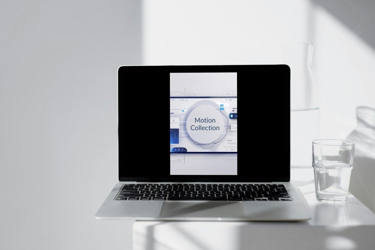 Laptop on a white surface with a glass of water and a whiteboard in the background
