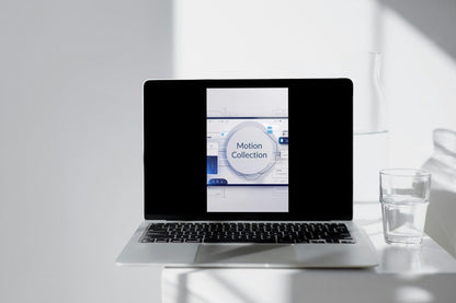 Laptop on a white surface with a glass of water and a whiteboard in the background